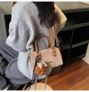 Detail of a brown plush Boston bag featuring a DoLun logo and a cute dog plush charm