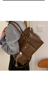Détail du grand sac cabas en cuir marron avec boucle dorée et breloque cheval