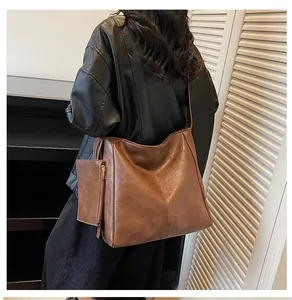 Detailed view of a vintage brown leather tote bag with a matching small zipper pouch