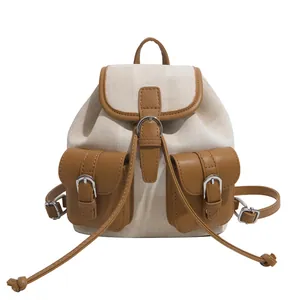 Detalle de mochila de lona beige con acabados de cuero marrón en los bolsillos