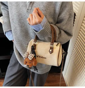 Detail view of cream faux fur baguette bag with brown handle and cute teddy bear charm