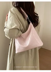 Sac fourre-tout rose pâle en cuir verni plissé porté avec un trench-coat élégant