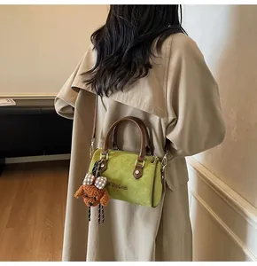 Detail view of green suede Boston bag with brown leather handles and a cute dog charm