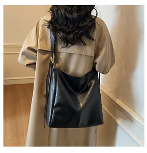 Detail of a large black leather tote bag with vertical stitching on a casual shoulder strap