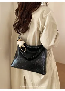 Détail d'un sac à bandoulière en cuir plissé brillant avec peluche et pendentif perle