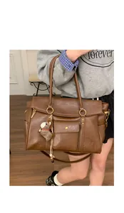 Détail d'un sac cabas en cuir marron foncé avec anneau doré et pendentif cheval