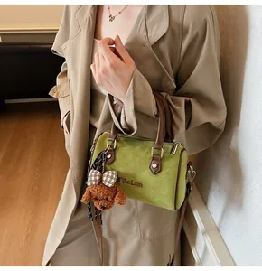 Detail of green suede Boston bag featuring M'DoLun embroidery and poodle charm
