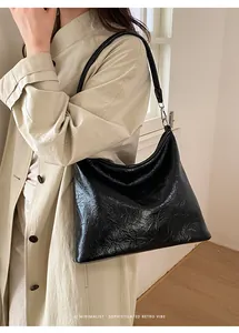 Détail d'un sac cabas noir froissé avec finition brillante et boucle en métal argenté