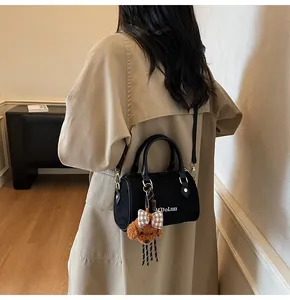 Detail of black Boston bag featuring M'DoLun logo and cute brown teddy bear pendant