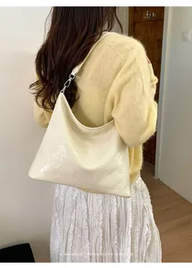 Détail du sac cabas en cuir froissé blanc crème porté par un mannequin en tenue décontractée