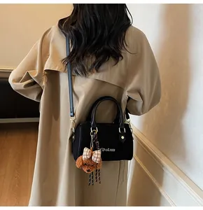 Detail of black Boston baguette bag with M'DoLun logo and cute puppy pendant accessory