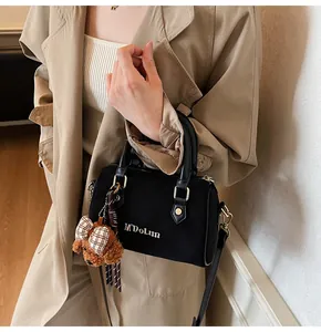 Detail of black suede Boston bag with gold hardware and a cute teddy bear charm