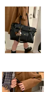 Détail d'un cabas en cuir noir avec ferrures dorées et pendentif cheval en peluche