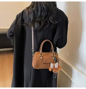 Detail of brown suede Boston bag with teddy charm and adjustable leather shoulder strap
