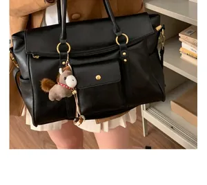 Détail d'un cabas vintage noir avec ferrures dorées et breloque peluche poney