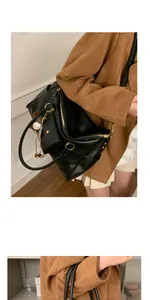 Détail d'un grand cabas en cuir noir avec ferrures dorées et breloque lapin en peluche