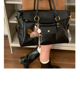 Détail du sac cabas noir en similicuir avec anneaux dorés et pendentif cheval en peluche