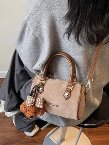 Brown frosted leather baguette bag with teddy charm shown on person in indoor setting