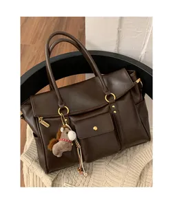 Détail du sac cabas en cuir marron foncé avec ferrures dorées et breloque poney