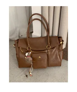 Détail du grand sac cabas marron vintage montrant la texture du cuir et la poche avant