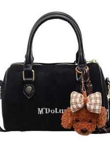 Elegant black suede baguette bag with leather handles and a brown plush teddy bear charm