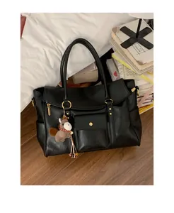 Détail d'un grand sac cabas noir avec garniture dorée et charm poney suspendu à la poignée