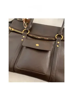 Détail d'un sac cabas vintage en cuir marron avec ferrures dorées et coutures