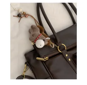 Détail de breloque poney en peluche avec perles de bois sur un sac à main en cuir