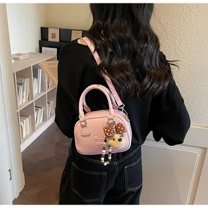 Detail van roze PU-leren crossbodytas met dierenreliëf en hanger van pluchen berenknuffel