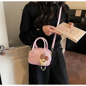 Detail van de roze crossbodytas van kunstleer met dierenreliëf en pluche hanger