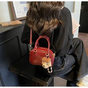 Detail van vintage donkerrode glanzende crossbodytas met schattige beer hanger decor