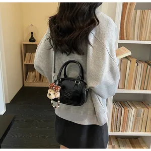 Detail van de glanzende zwarte mini Boston tas met een schattige pluche beer aan de riem