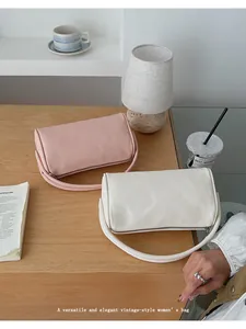 Details von rosa und weißen zylindrischen Lederhandtaschen auf Holztisch mit Kaffeetasse