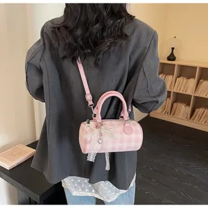 Pink and white checkered cylinder bag with pearl bow charms worn by model