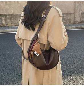 Detail of dark brown hobo bag with teddy bear charm and striped scarf decoration