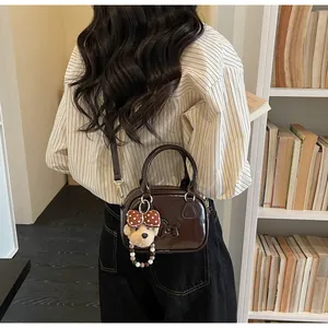 Detail van retro donkerbruine crossbodytas met schattige teddybeer hanger