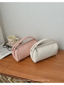 Detailansicht von Leder-Baguette-Taschen in Rosa und Beige mit Reißverschluss auf Holz