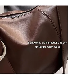Close-up of brown leather texture with detailed stitching and metal hardware on tote bag