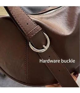 Detail of silver hardware buckle and adjustable shoulder strap on dark brown leather tote bag