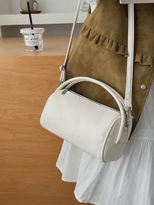 Weiße minimalistische Barrel-Tasche aus Kunstleder mit Rundgriff und verstellbarem Riemen im Alltag