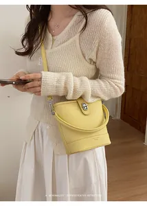 Detail of yellow bucket bag featuring lychee grain leather and metal turn-lock closure