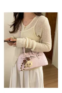 Detail of pink vintage shell bag featuring silver hardware and a cute plush bear charm