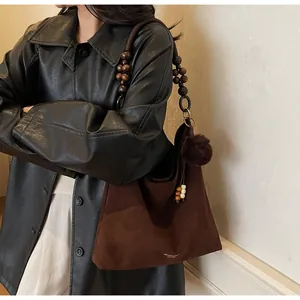 Detail of dark brown suede hobo bag featuring a unique wooden bead shoulder strap