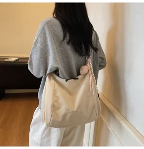 Detail view of large beige canvas crossbody bag with teddy bear charm and silk scarf