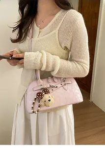 Detail of elegant pink faux leather shell bag with cute plush bear charm accessory