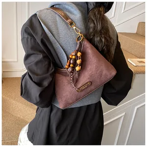 Close-up of dark brown suede hobo bag with vintage wooden beads and gold-tone hardware