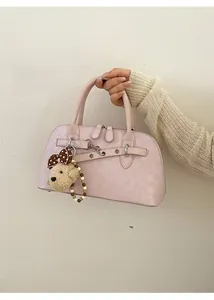 Close-up of pink textured shell handbag with metallic zip and cute bear pendant charm