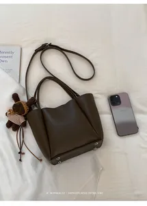 Détail du sac seau en cuir grainé marron foncé avec un joli pendentif ours en peluche