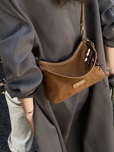 Brown suede dumpling bag with half-moon shape and decorative beaded charm pendant