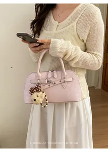 Pink matte shell bag featuring decorative straps and a cute plush bear pendant accessory